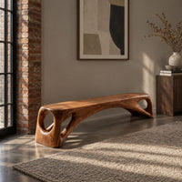 Low solid wood bench with an arched underside and open cutouts at each end in an industrial loft entryway with exposed brick