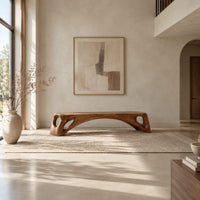 Low solid wood bench with an arched underside and open cutouts at each end in a bright open plan entryway