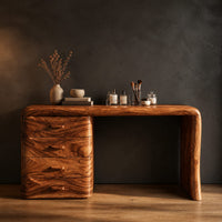 Makeup vanity desk with four wave carved drawers and a single slab leg in a dark studio against a charcoal plaster wall
