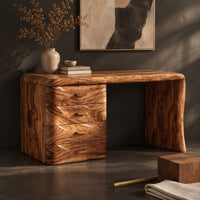 Corner detail of makeup vanity desk with four wave carved drawers and a single slab leg beside wood, brass and linen samples