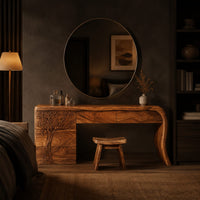 Makeup vanity with a carved tree pedestal and a sweeping slab leg in a dark bedroom at golden hour