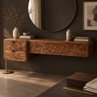 Corner detail of makeup vanity with a carved vine panel, two drawers and a slim post leg beside wood, brass and linen samples