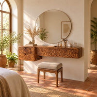 Makeup vanity with a carved vine panel, two drawers and a slim post leg in a bright bedroom with arched windows and plants