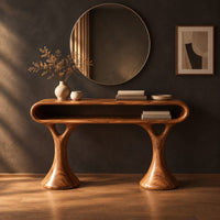 Makeup vanity with a pill shaped open shelf top and flared pedestal legs in a dark studio against a charcoal plaster wall