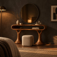 Makeup vanity with a pill shaped open shelf top and flared pedestal legs in a dark bedroom at golden hour