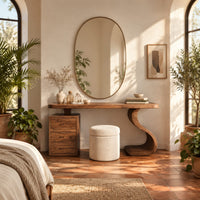 Makeup vanity with an s curve pedestal and a three drawer cabinet in a bright bedroom with arched windows and plants