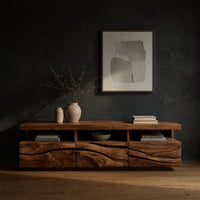 Media cabinet with open cubbies above carved wave drawers in a dark studio against a charcoal wall