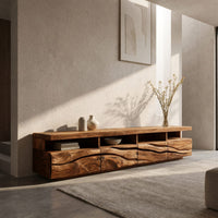 Media cabinet with open cubbies above carved wave drawers in an open plan space in daylight