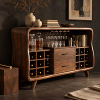 Corner detail of mid century bar cabinet with a curved frame, square cubbies and two drawers beside wood, brass and linen samples