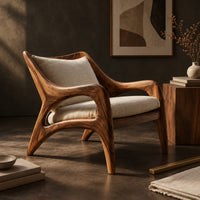 Corner detail of wooden armchair with sweeping sculpted arms and splayed legs beside wood, brass and linen samples