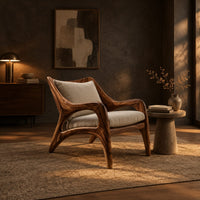 Wooden armchair with sweeping sculpted arms and splayed legs in a dark living room at golden hour