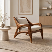 Wooden armchair with sweeping sculpted arms and splayed legs in a Scandinavian living room with white walls