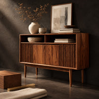 Corner detail of mid century console table with fluted front and tapered legs beside wood, brass and linen samples