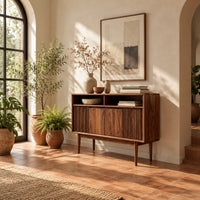 Mid century console table with fluted front and tapered legs in a bright entryway with arched windows and plants