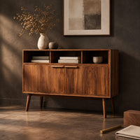 Corner detail of mid century console table with three open cubbies and two doors on tapered legs beside wood, brass and linen samples