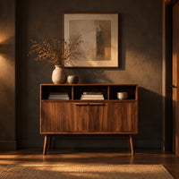 Mid century console table with three open cubbies and two doors on tapered legs in a dark entryway at golden hour