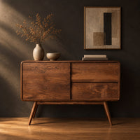 Low cabinet style console table with three wood panels on splayed legs in a dark studio against a charcoal plaster wall