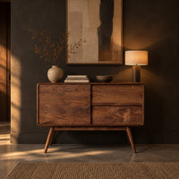 Low cabinet style console table with three wood panels on splayed legs in a dark entryway at golden hour