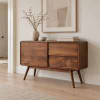 Low cabinet style console table with three wood panels on splayed legs in a Scandinavian entryway with white walls