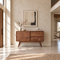 Low cabinet style console table with three wood panels on splayed legs in a bright open plan entryway