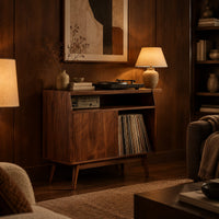 Mid century record player stand with one flat door and tapered legs in an evening living room with walnut wall paneling
