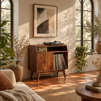 Mid century record player stand with one flat door and tapered legs in a bright living room with arched windows and plants