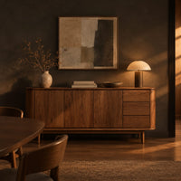 Mid century sideboard with three drawers and tapered legs in a dark dining room at golden hour