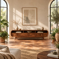 Low tv stand with pill shaped ends, three open cubbies and slim tapered legs in a bright living room with arched windows and plants