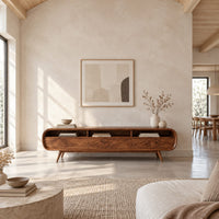 Low tv stand with pill shaped ends, three open cubbies and slim tapered legs in a bright open plan living room