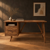Mid century desk with a drawer pedestal, open cubby and angled trestle legs in a dark studio against a charcoal plaster wall