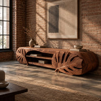 Long tv stand with monstera leaf carved ends and open shelves in the center in an industrial loft living room with exposed brick