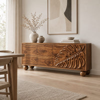 Sideboard with a carved monstera leaf on the right doors and ball feet in a Scandinavian dining room with white walls