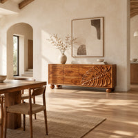 Sideboard with a carved monstera leaf on the right doors and ball feet in a bright open plan dining room