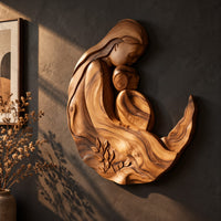 Carved wooden mother and child wall sculpture in a flowing crescent shape, three-quarter view showing the carved depth