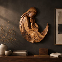 Detail of carved wooden mother and child wall sculpture in a flowing crescent shape beside wood, brass and linen samples