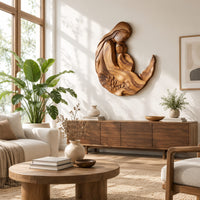 Carved wooden mother and child wall sculpture in a flowing crescent shape in a bright sunroom with green plants