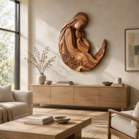 Carved wooden mother and child wall sculpture in a flowing crescent shape above a light oak sideboard in daylight