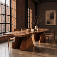 Live edge dining table on two wedge pedestals with jagged peak tops in an industrial loft dining room with exposed brick