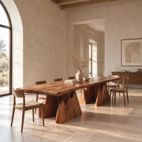 Live edge dining table on two wedge pedestals with jagged peak tops in a bright open plan dining room