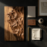 Detail of four panel carved mountain wall art set beside wood, brass and linen samples
