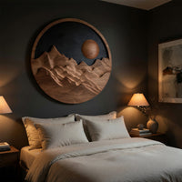 Round wooden mountain wall hanging with a black sky above a bed in a dusk lit bedroom