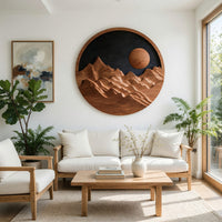 Round wooden mountain wall hanging with a black sky in a bright sunroom with green plants