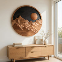 Round wooden mountain wall hanging with a black sky above a light oak sideboard in daylight