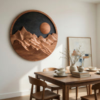 Round wooden mountain wall hanging with a black sky beside a dining table in natural light