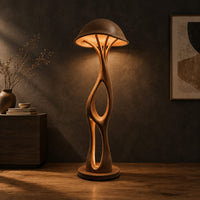 Mushroom canopy floor lamp with a slender sculpted stem and disc base in a dark studio against a charcoal plaster wall