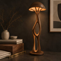 Corner detail of mushroom canopy floor lamp with a slender sculpted stem and disc base beside wood, brass and linen samples