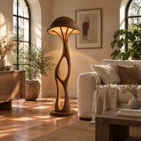Mushroom canopy floor lamp with a slender sculpted stem and disc base in a bright living room with arched windows and plants