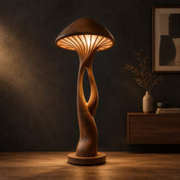 Floor lamp with a mushroom cap shade and a sculpted open stem in a dark studio against a charcoal plaster wall