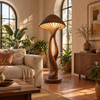 Floor lamp with a mushroom cap shade and a sculpted open stem in a bright living room with arched windows and plants