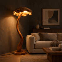 Floor lamp with a winding wooden stem and a wavy mushroom cap shade in a dark living room at golden hour